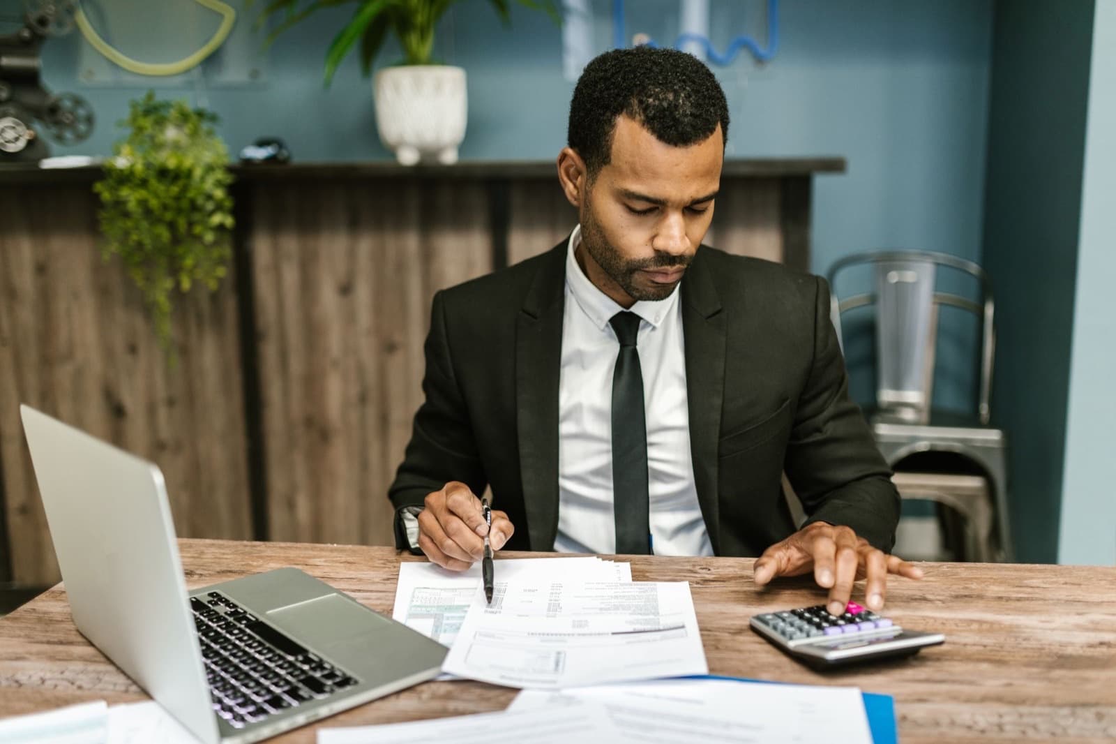 A professional reviewing documents alongside a laptop